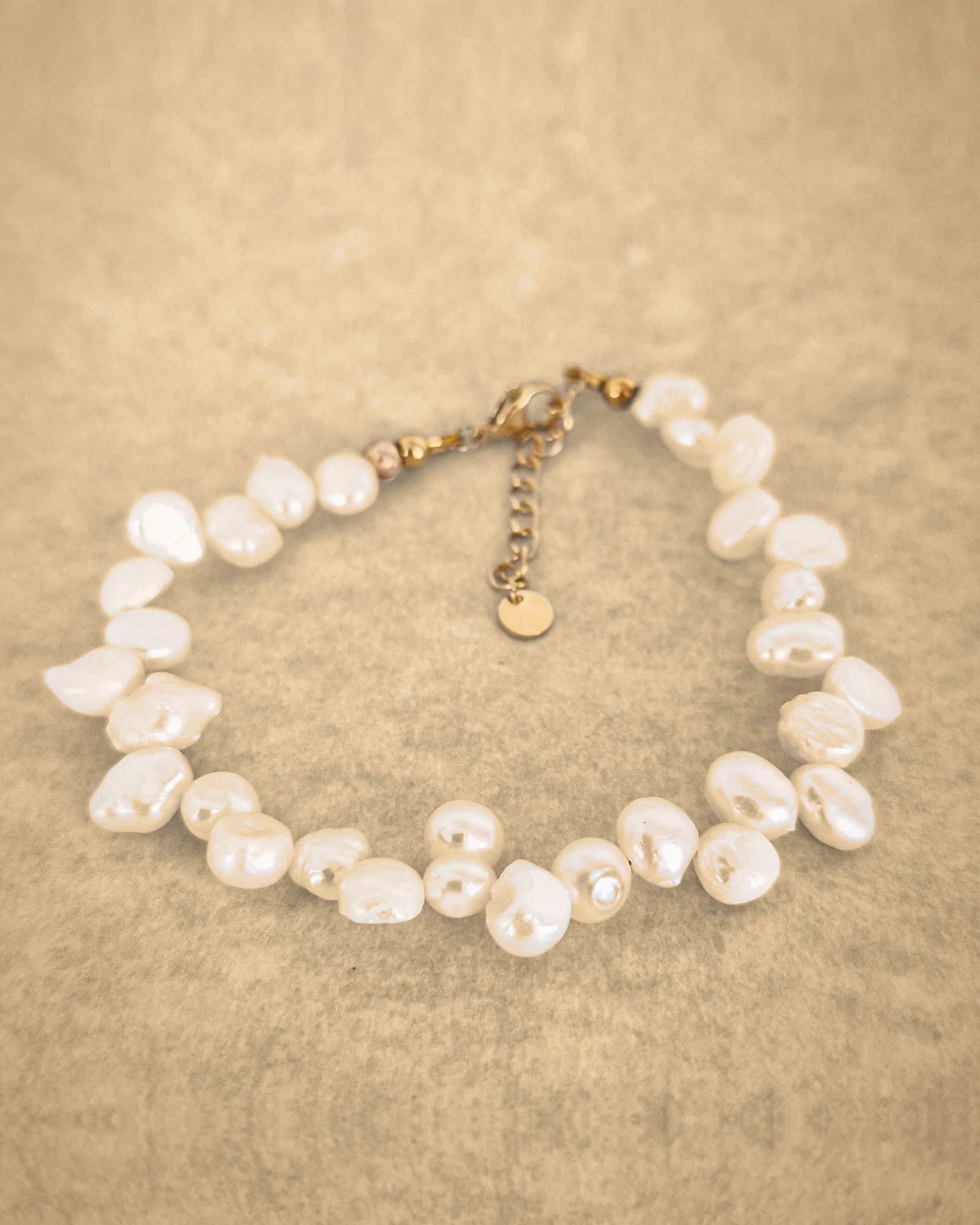 Pearl anklet of irregular pearls with a gold-tone lobster clasp, an extension chain and a round charm